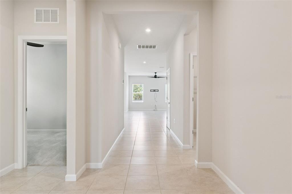 A tiled hallway leads from a carpeted room toward an open living area with windows — 2106 HAVASU FALLS DRIVE, DELAND, FL
