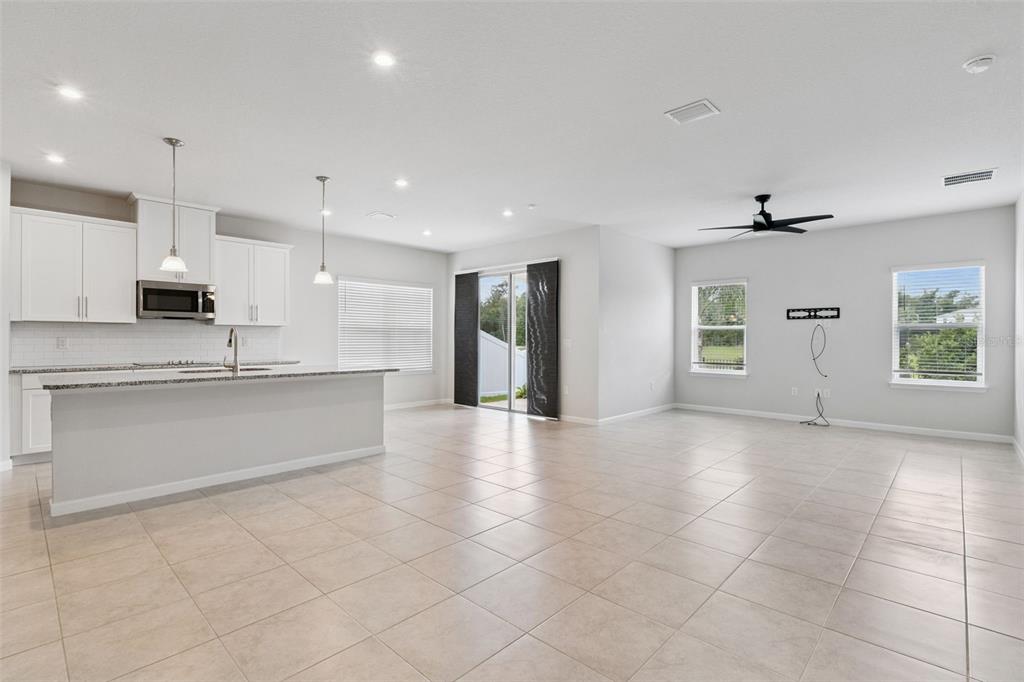 An open-concept kitchen and living area featuring white cabinets, granite countertops, and tile flooring — 2106 HAVASU FALLS DRIVE, DELAND, FL