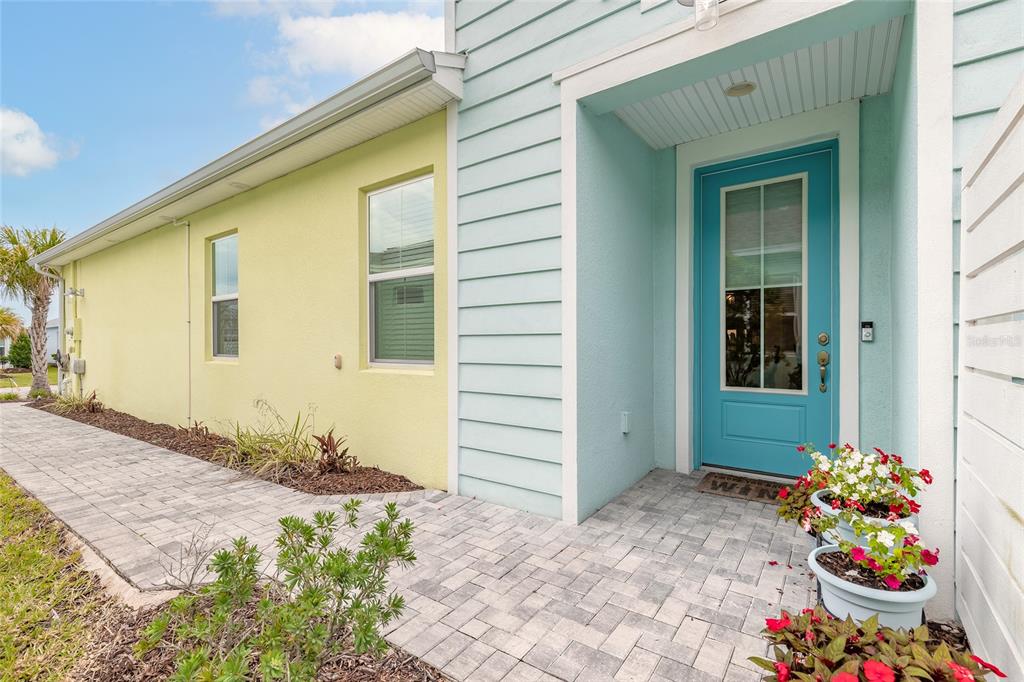 A light blue front door sits beside a yellow wall and a paved walkway — 230 SAND BAR LANE, DAYTONA BEACH, FL