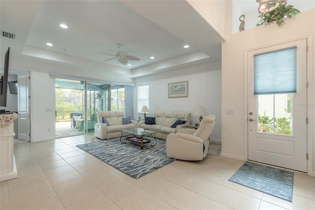 A bright living room features tile floors, a tray ceiling, and sliding glass doors — 230 SAND BAR LANE, DAYTONA BEACH, FL