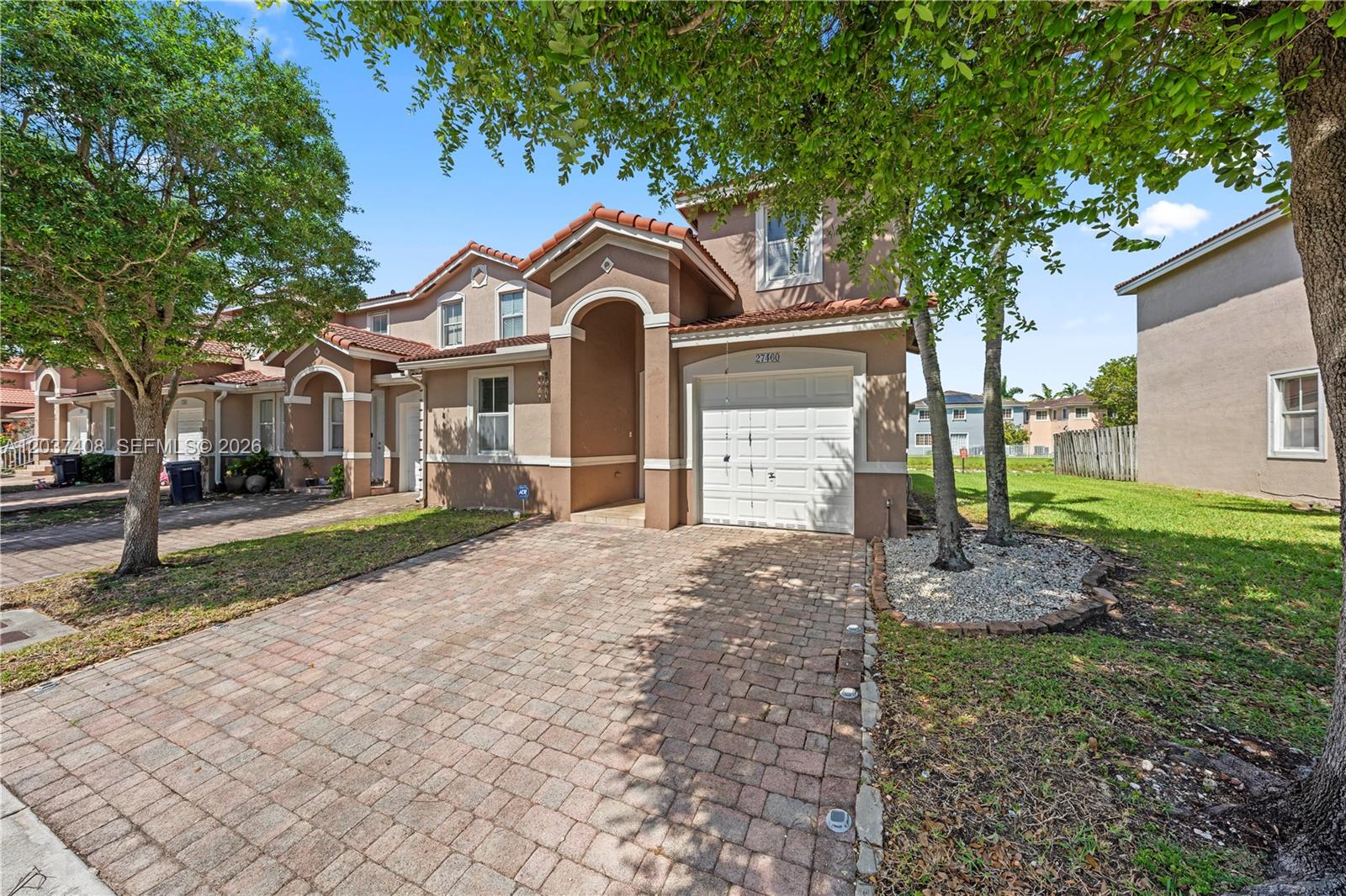A two-story tan stucco townhouse features a brick paver driveway and a single-car garage — 27460 SW 138th Path, Homestead FL 33032, HOMESTEAD, FL