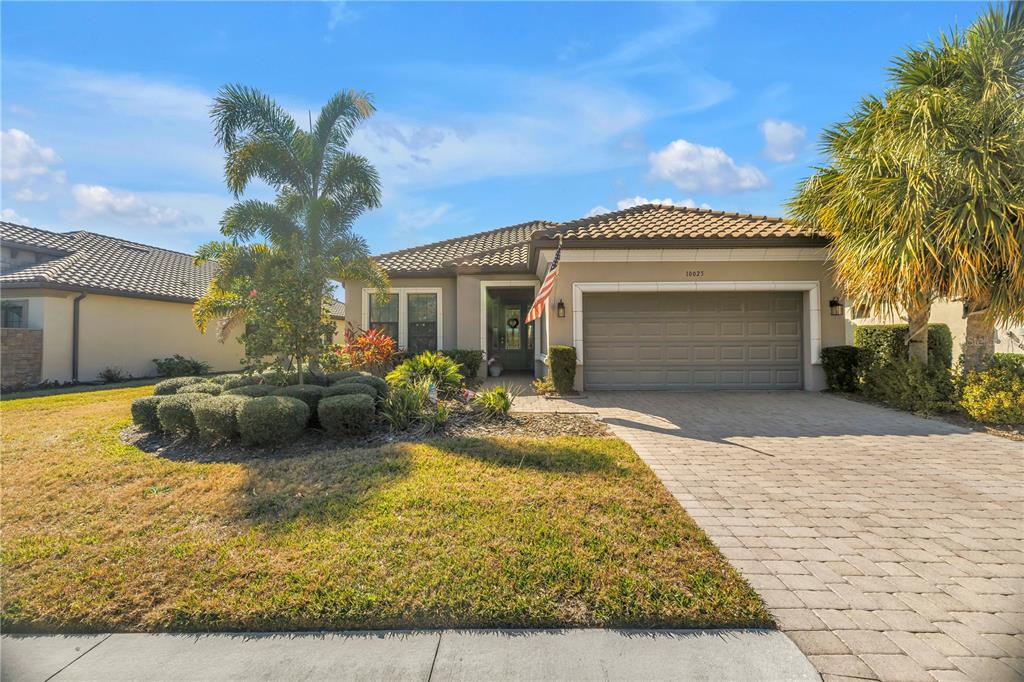 A single-story house with a paved driveway, a two-car garage, and palm trees — 10025 CRAFTSMAN PARK WAY, PALMETTO, FL