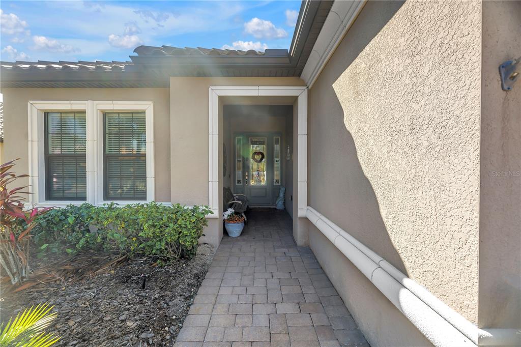 A paved walkway leads to the front entrance of a house with a light-colored exterior — 10025 CRAFTSMAN PARK WAY, PALMETTO, FL