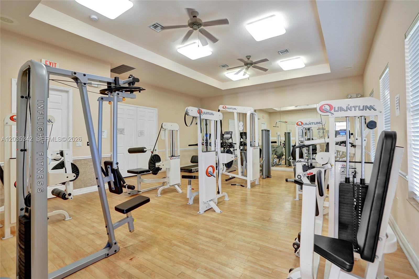 A gym room features multiple weight machines, light wood flooring, and recessed ceiling lights — MIRAMAR, FL