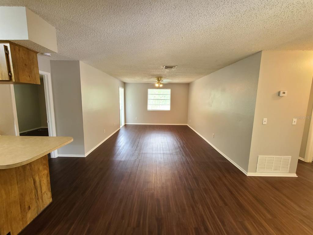 An open-concept living area features dark wood-look flooring, light-colored walls, and a ceiling fan — 205 RED MAPLE PLACE UNIT 205, BRANDON, FL