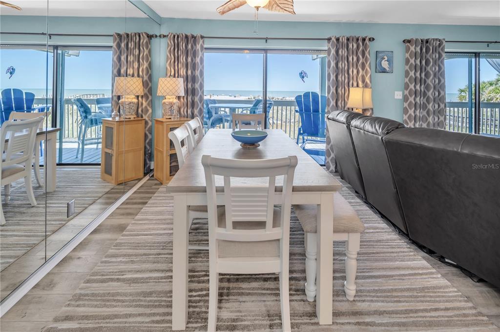 A dining area features a wooden table, white chairs, and a view of the ocean — 200 120TH AVENUE W UNIT 3A, TREASURE ISLAND, FL