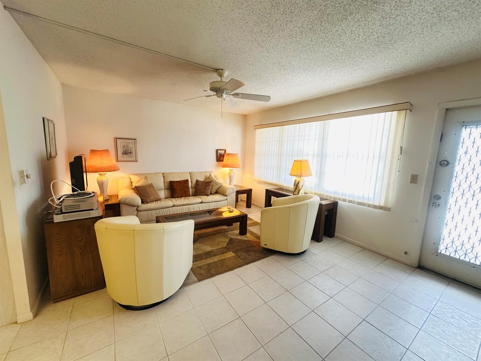 A living room features a beige sofa, two cream armchairs, a coffee table, and tile flooring — 2060 Harwood E # 2060, Deerfield Beach FL 33442, DEERFIELD BEACH, FL