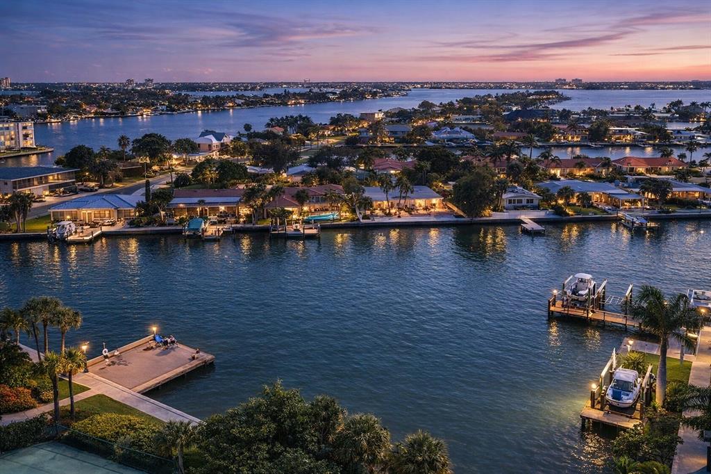 An aerial view of waterfront homes, docks, and boats at sunset along a canal — 5353 GULF BOULEVARD UNIT A404, ST PETE BEACH, FL
