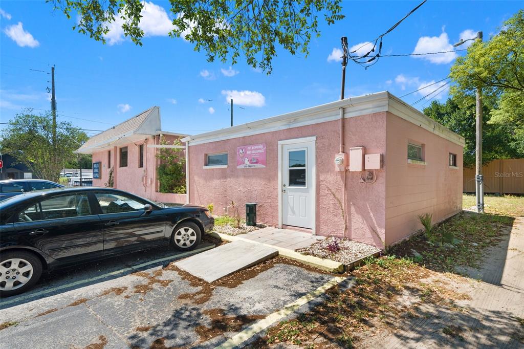 A pink, single-story commercial building with a white door and a parked black car — 6603 N FLORIDA AVENUE, TAMPA, FL