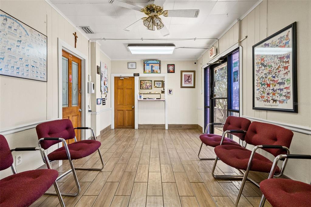 A waiting room features wood-look tile flooring, burgundy chairs, and dog-themed wall art — 6603 N FLORIDA AVENUE, TAMPA, FL