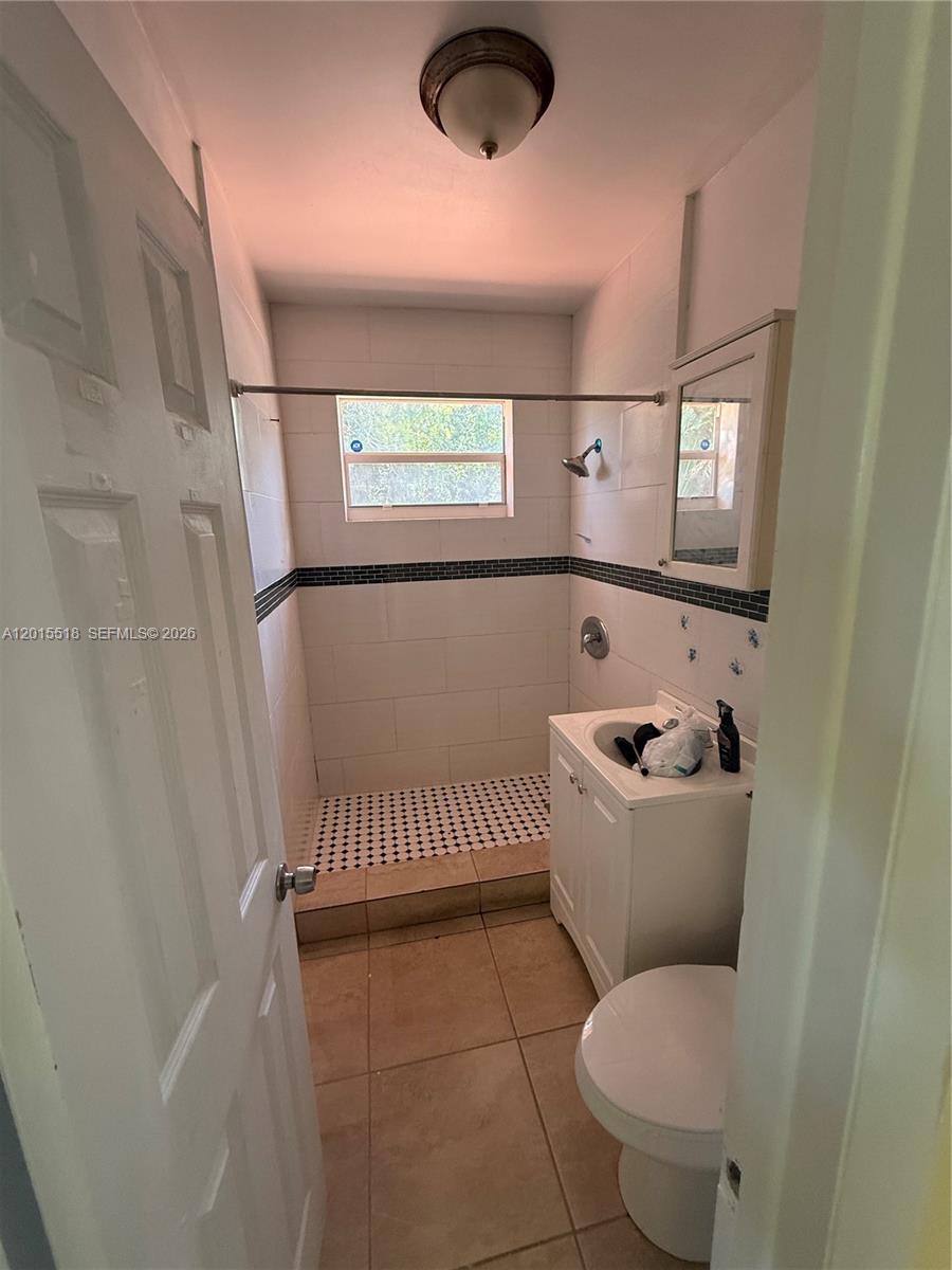 A small bathroom features a tiled walk-in shower, a white vanity, and a toilet — NORTH MIAMI BEACH, FL