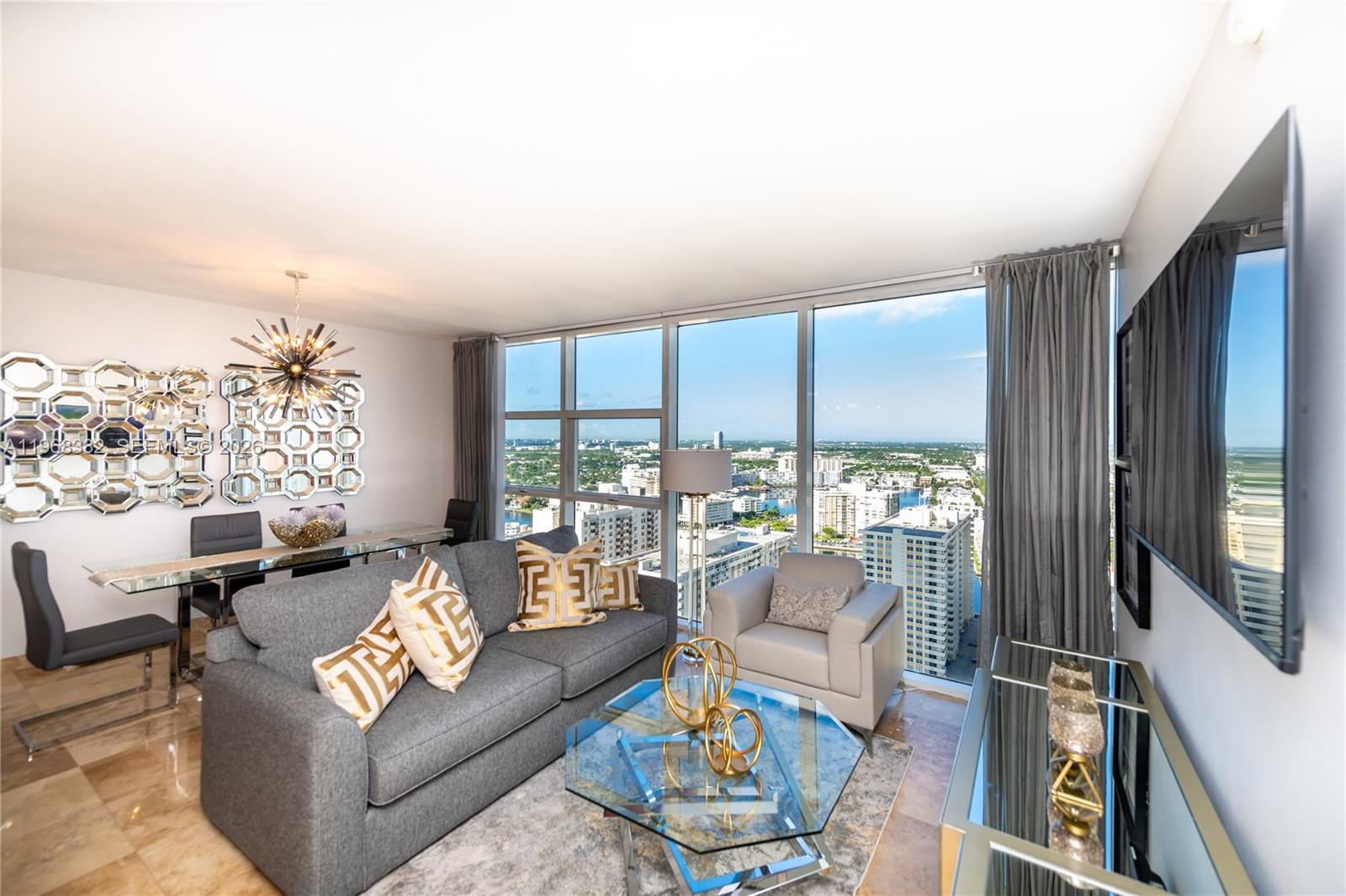 A modern living and dining room features floor-to-ceiling windows with expansive city views — 1830 S Ocean Dr # 2907, Hallandale Beach FL 33009, HALLANDALE BEACH, FL