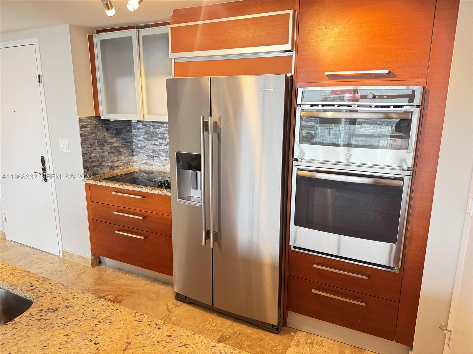 A kitchen features wood cabinets, stainless steel appliances, a stone countertop, and tile flooring — 1830 S Ocean Dr # 2907, Hallandale Beach FL 33009, HALLANDALE BEACH, FL