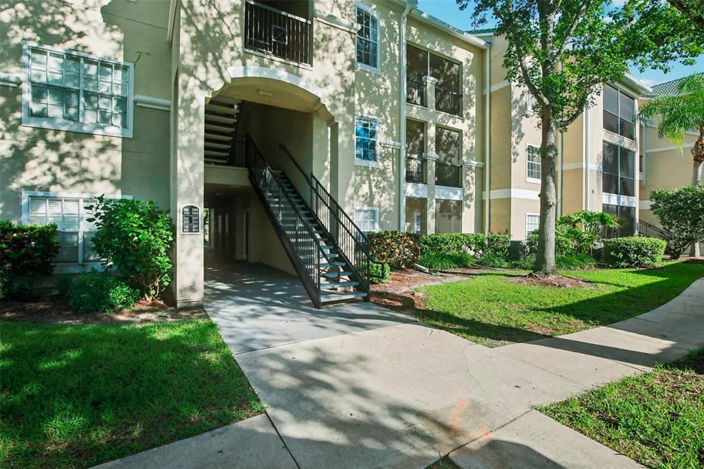 An exterior view of a multi-story apartment building with an outdoor staircase and landscaped grounds — 5174 NORTHRIDGE ROAD UNIT 104, SARASOTA, FL