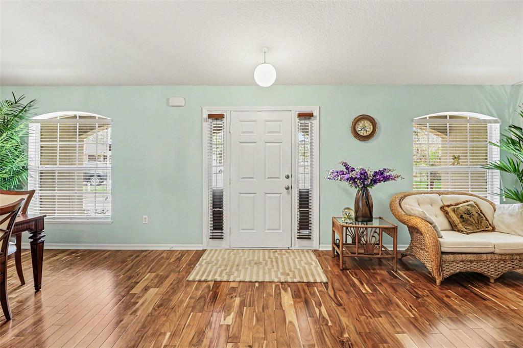 A light green entryway features a white front door, wood flooring, and a wicker sofa — 100 FESTIVE COURT, CHULUOTA, FL