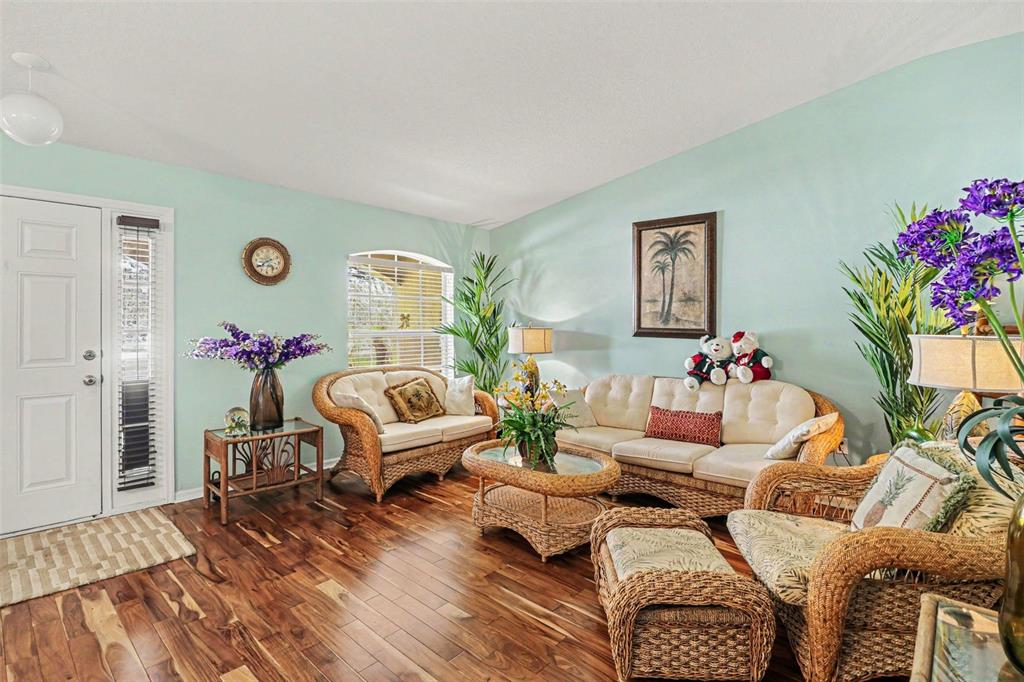 A living room features light blue walls, wicker furniture, and dark wood flooring — 100 FESTIVE COURT, CHULUOTA, FL