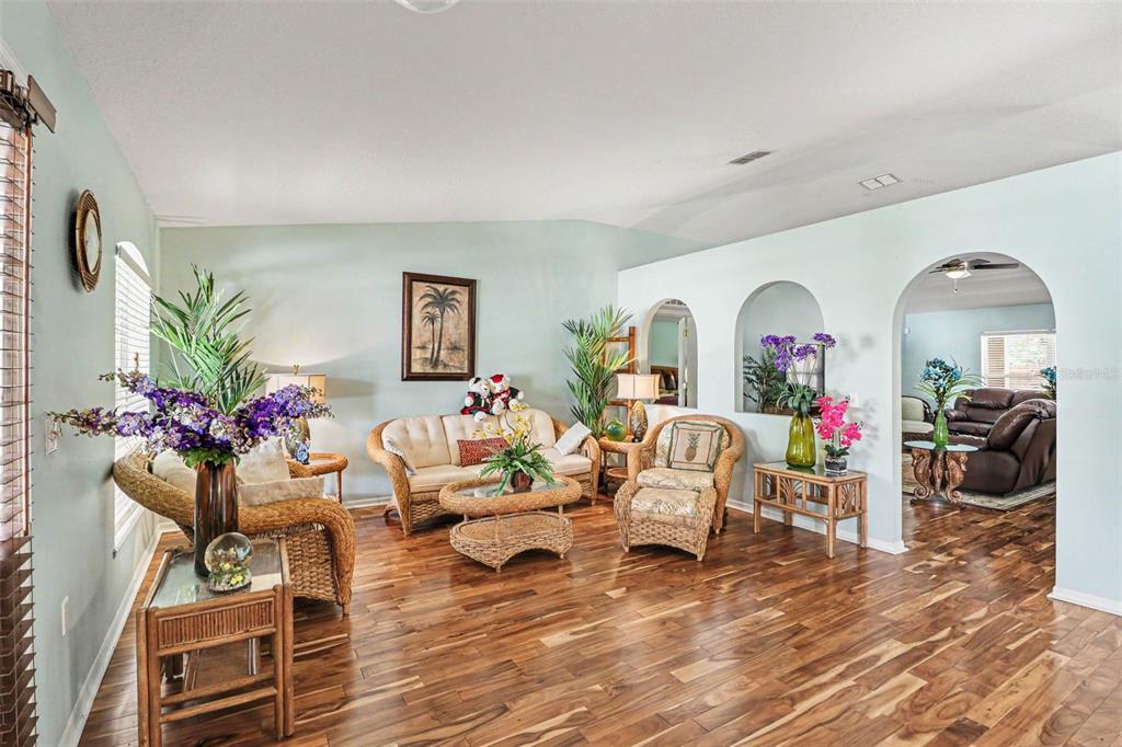 A living room with wicker furniture, hardwood floors, and arched wall openings — 100 FESTIVE COURT, CHULUOTA, FL