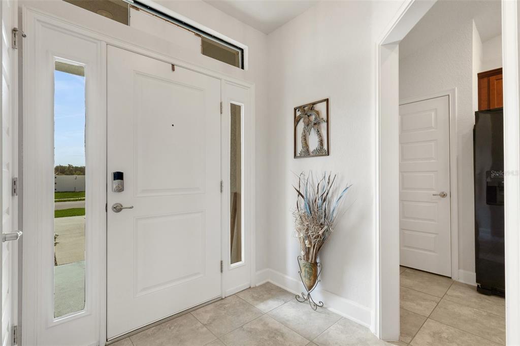 An entryway with a white front door, tile flooring, and a doorway leading to a kitchen — 220 HERITAGE PARK LANE, MULBERRY, FL
