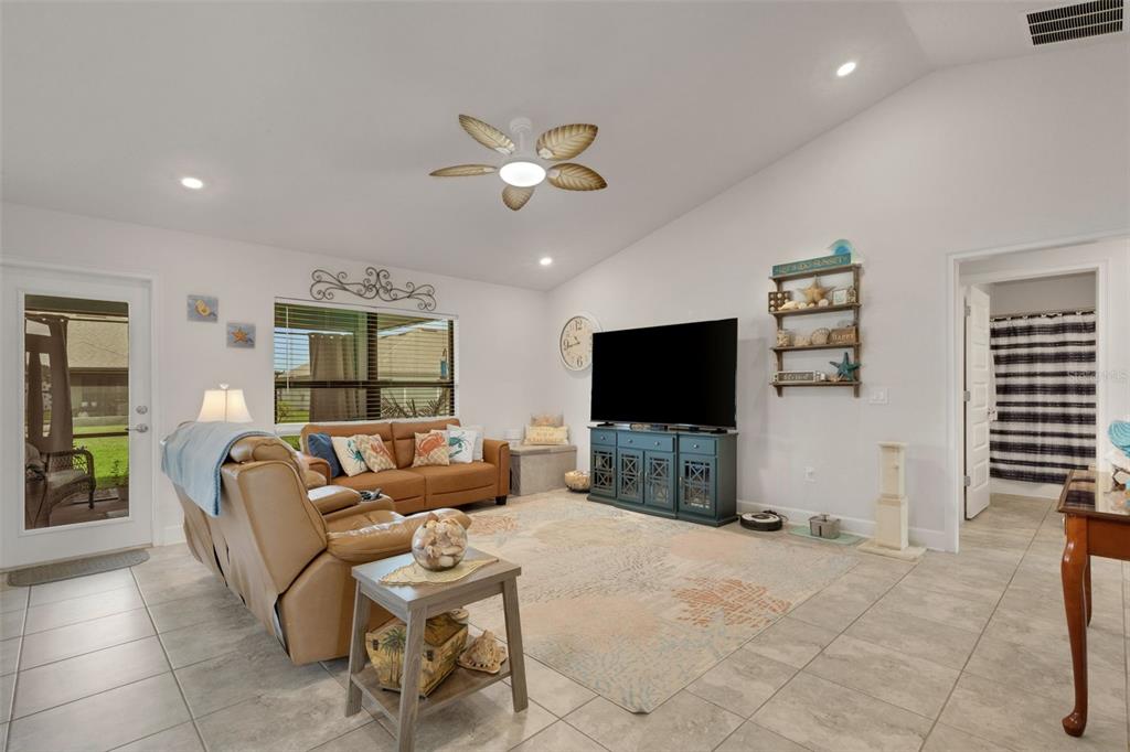 A living room features tile flooring, a tan sofa, a television console, and a ceiling fan — 220 HERITAGE PARK LANE, MULBERRY, FL