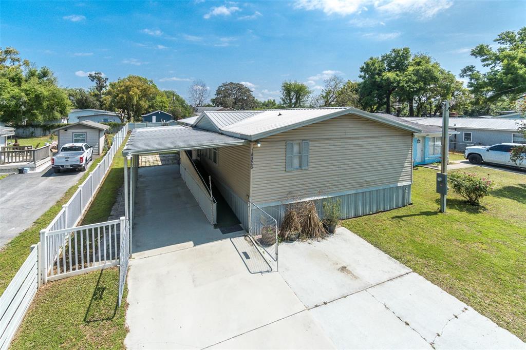 An exterior view of a tan mobile home with a metal roof and attached carport — 14926 DOUGLAS STREET, DADE CITY, FL
