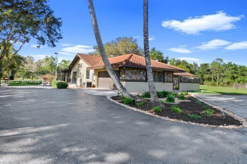 A paved walkway leads to a single-story house surrounded by palm trees and a lawn — 3761 Dellwood Blvd., Loxahatchee FL 33470, LOXAHATCHEE, FL