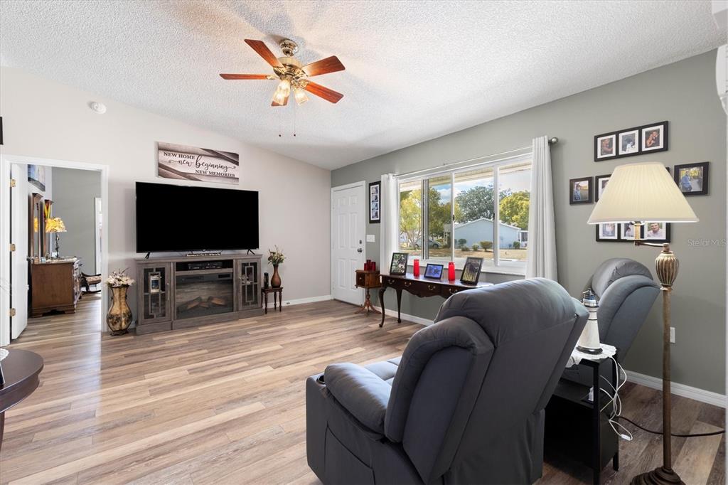 A living room features wood-look flooring, a ceiling fan, a television console, and two recliners — 17587 SE 96TH COURT, SUMMERFIELD, FL