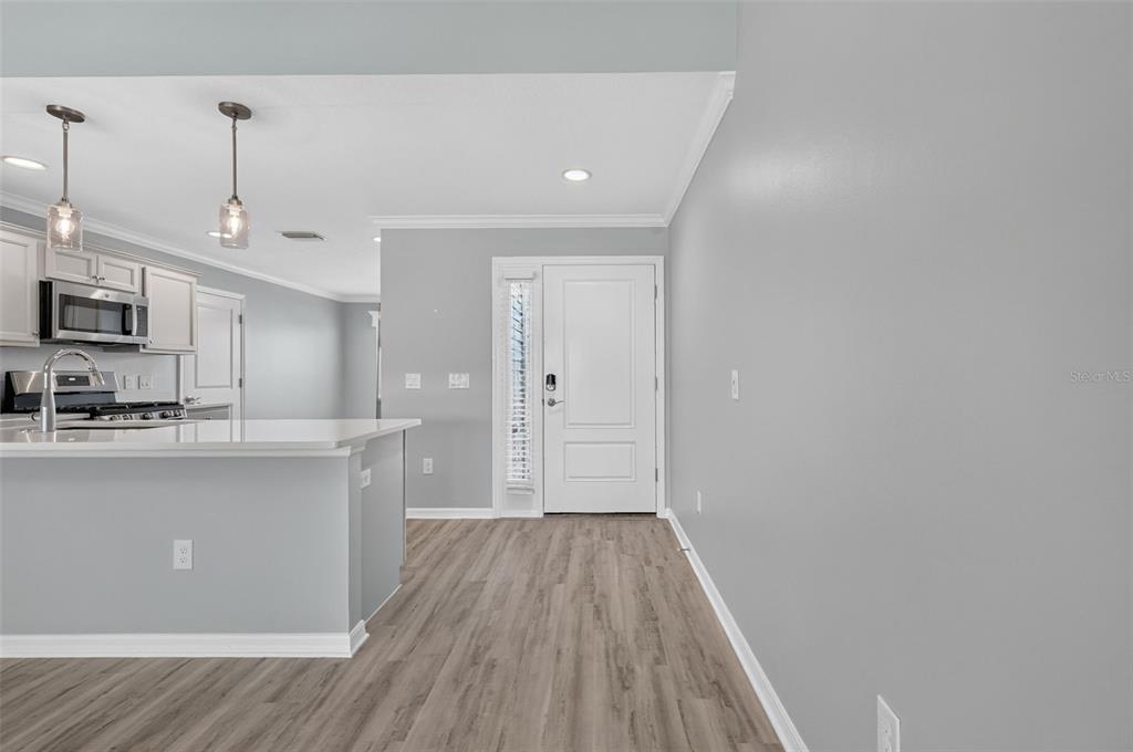 A kitchen with a breakfast bar and light gray walls leads to a white front door — 1742 JAMES GRAY STREET, THE VILLAGES, FL