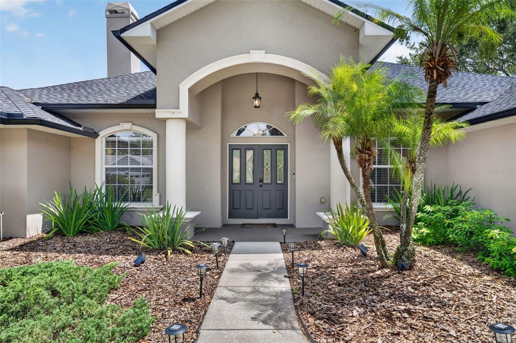 A front exterior view of a house with a gray double door and arched entryway — 4911 RAYLENE WAY, ST CLOUD, FL