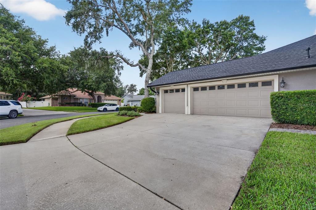 A concrete driveway leads to a three-car garage in front of a suburban house — 4911 RAYLENE WAY, ST CLOUD, FL