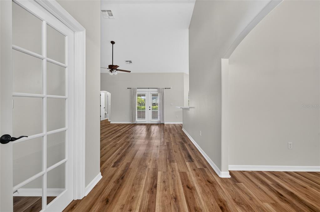A view from a hallway looking into a living area with wood-look flooring — 4911 RAYLENE WAY, ST CLOUD, FL