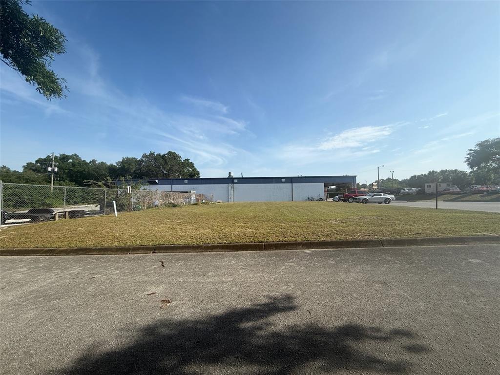 A vacant, grassy lot sits in front of a long, white commercial building — SW 22 PLACE, OCALA, FL