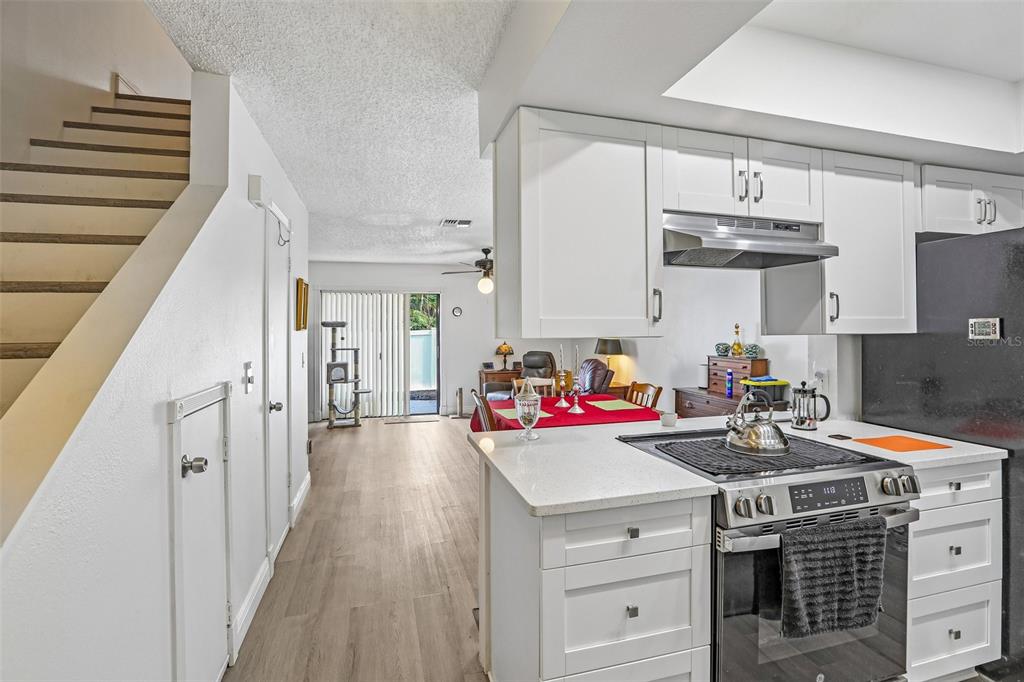 A kitchen with white cabinets and a gas range overlooks a dining area and stairs — 4005 OAK LIMB COURT, TAMPA, FL