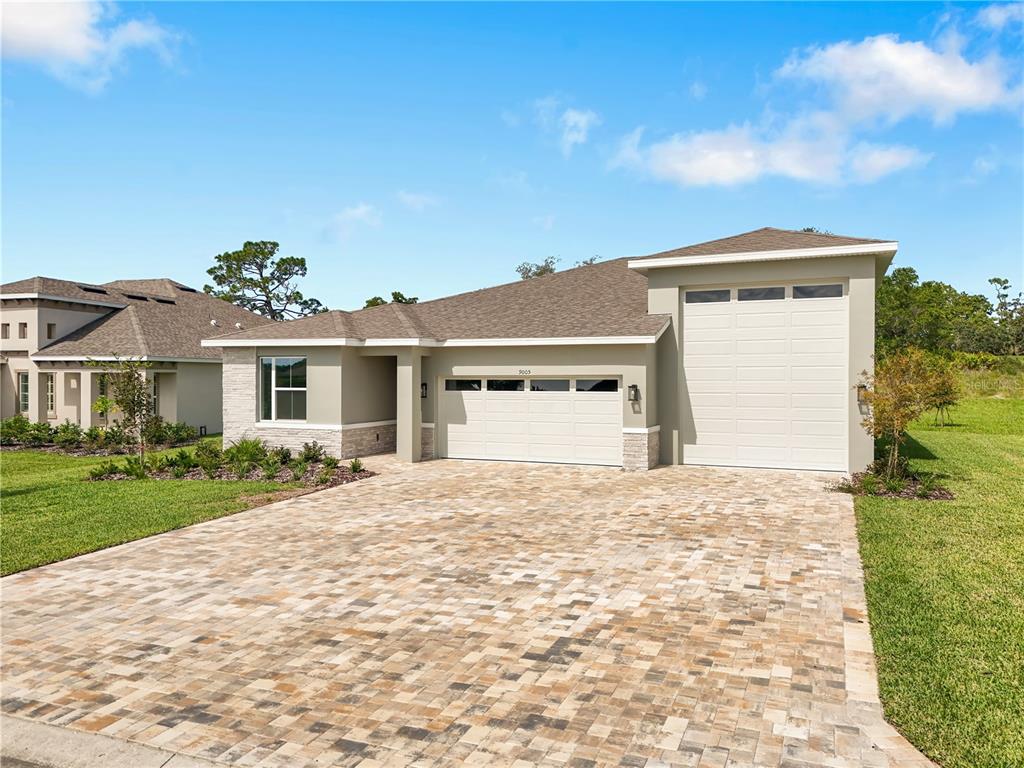 A single-story house with a paved driveway, two garage doors, and light-colored exterior walls — 9005 PLAYERS DRIVE, WEEKI WACHEE, FL