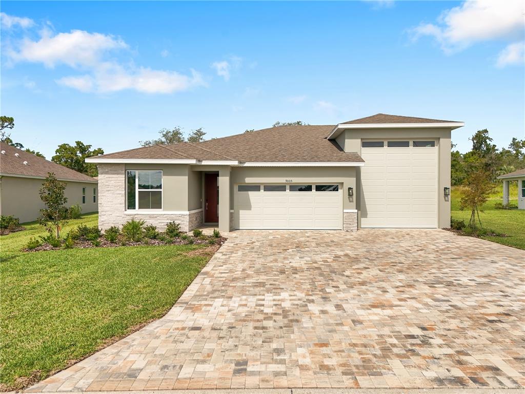 A single-story house with a paved driveway, stone accents, and a two-car garage — 9005 PLAYERS DRIVE, WEEKI WACHEE, FL