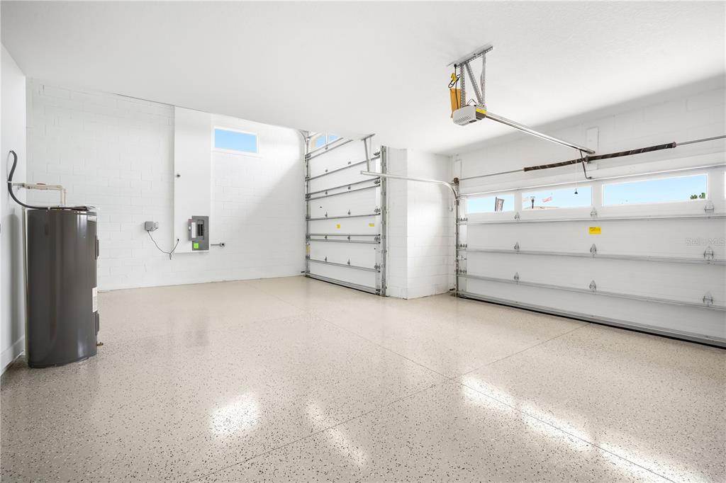 A clean garage with a speckled epoxy floor, white block walls, and two garage doors — 9005 PLAYERS DRIVE, WEEKI WACHEE, FL