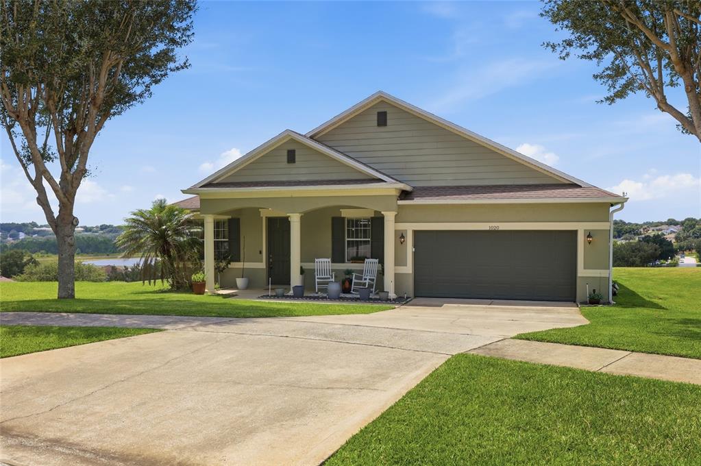 A single-story house with a green exterior, a two-car garage, and a covered front porch — 1020 SAILING BAY DR, CLERMONT, FL