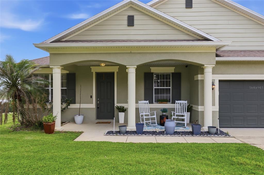 The exterior of a house features a covered front porch with columns and rocking chairs — 1020 SAILING BAY DR, CLERMONT, FL
