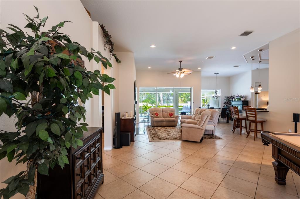 An open-concept living area features tile flooring, a pool table, and a view of the patio — 21023 LOS CABOS COURT, LAND O LAKES, FL