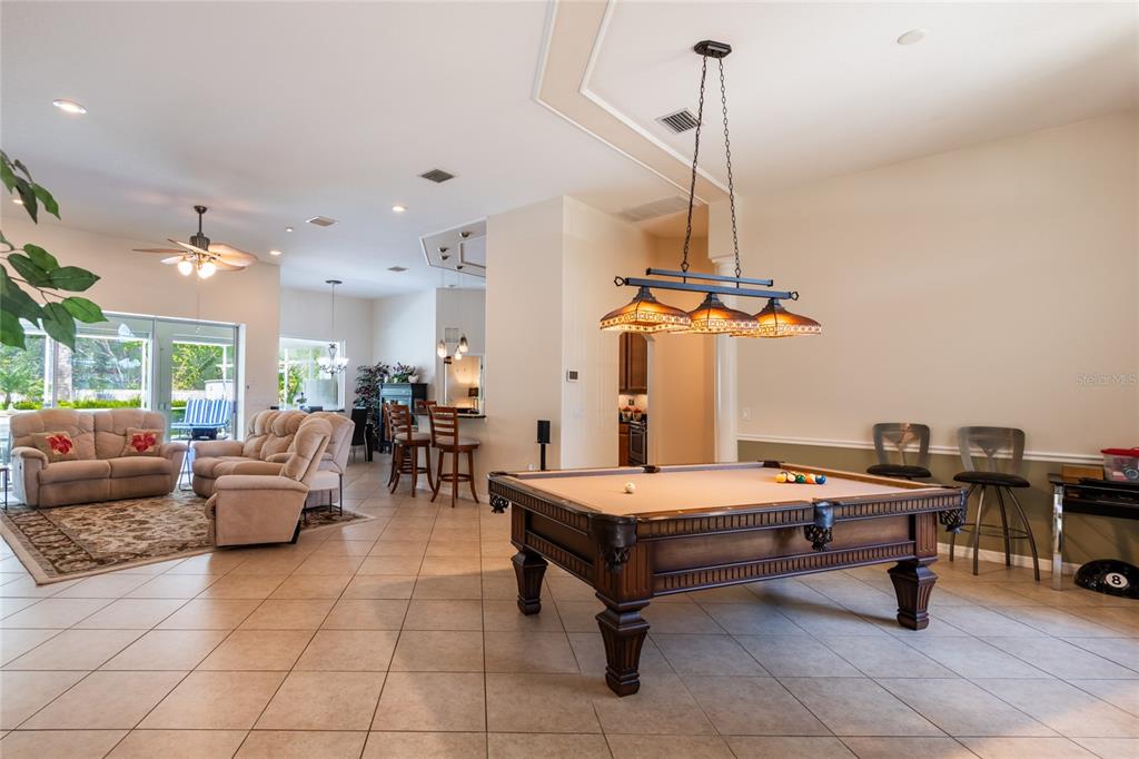 A spacious room features a pool table, beige tile flooring, and an adjacent living area — 21023 LOS CABOS COURT, LAND O LAKES, FL