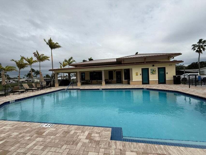 A swimming pool sits in front of a single-story clubhouse with a covered patio — 6085 Seashore Drive, Atlantis FL 33462, ATLANTIS, FL