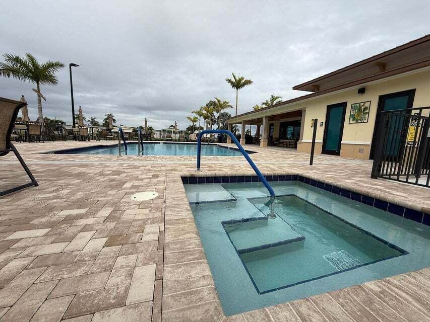 A spa and swimming pool are set on a paved patio beside a building — 6085 Seashore Drive, Atlantis FL 33462, ATLANTIS, FL