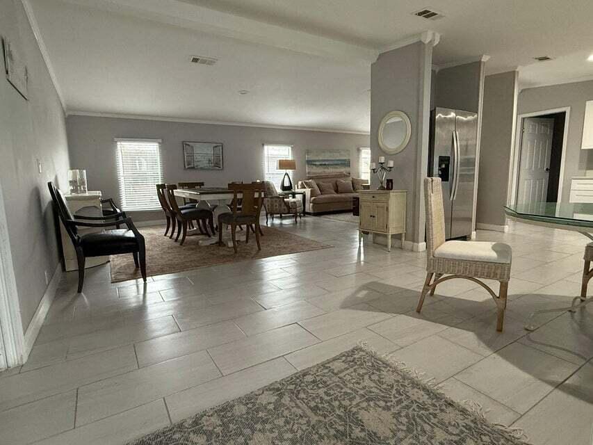 An open-concept living and dining area features light tile flooring and neutral gray walls — 6085 Seashore Drive, Atlantis FL 33462, ATLANTIS, FL