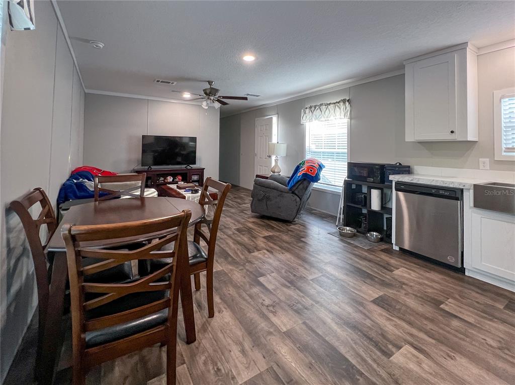 An open-concept living and dining area features wood-look flooring and a kitchen with stainless appliances — 12203 LANTANA AVENUE, NEW PORT RICHEY, FL
