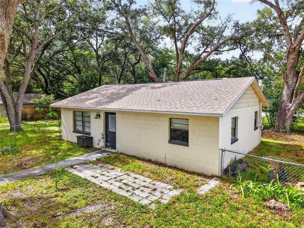 A small, single-story house with cream-colored concrete block walls and a shingled roof — 1454 HOWARD STREET, GROVELAND, FL