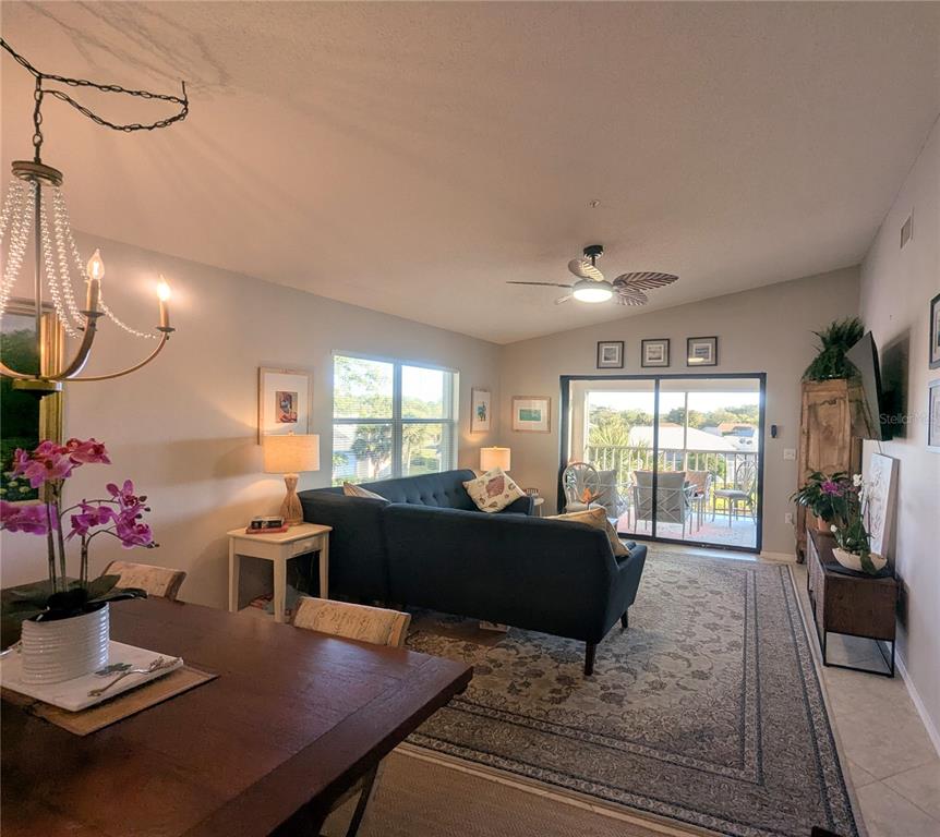 A living room with a dark blue sectional, dining area, and sliding doors to a balcony — 9300 CLUBSIDE CIRCLE UNIT 1308, SARASOTA, FL
