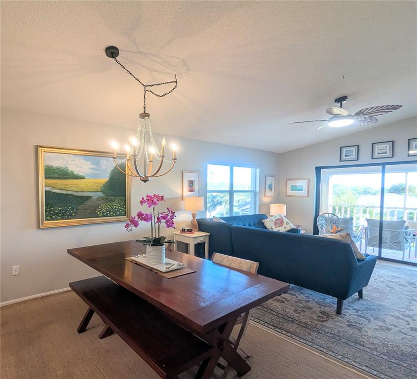 A dining area with a wooden table and bench sits before a living room space — 9300 CLUBSIDE CIRCLE UNIT 1308, SARASOTA, FL