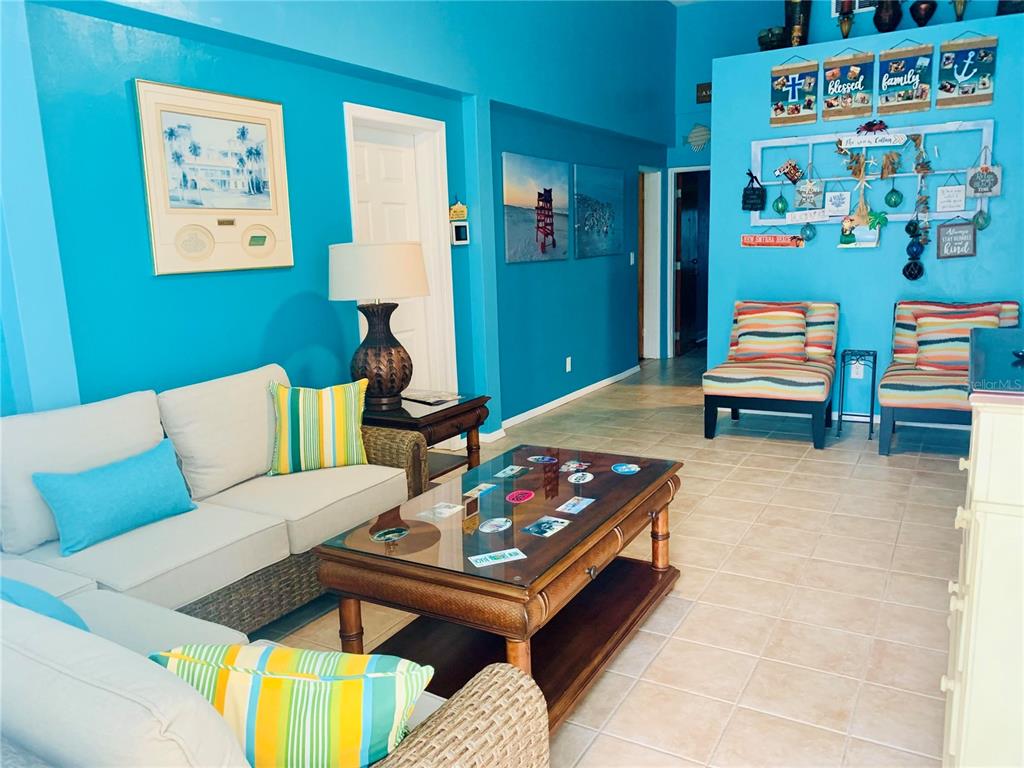 A living room with bright blue walls, a beige sofa, and a glass-topped coffee table — 813 N ATLANTIC AVENUE, NEW SMYRNA BEACH, FL
