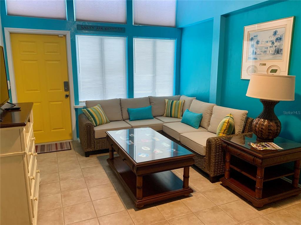 A living room features a wicker sectional sofa, a glass-topped coffee table, and turquoise walls — 813 N ATLANTIC AVENUE, NEW SMYRNA BEACH, FL