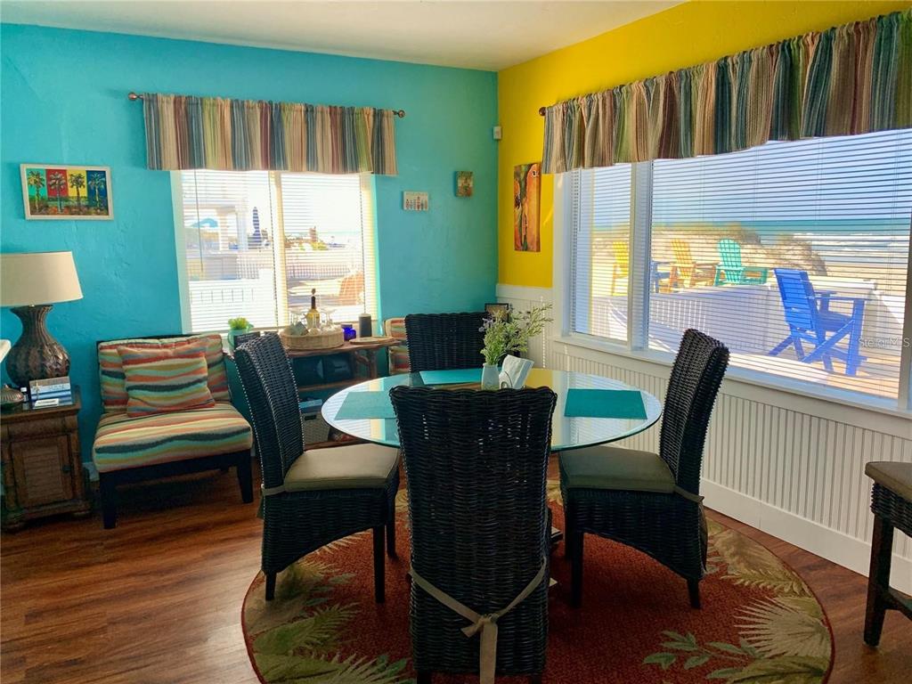 A dining area features a glass table, wicker chairs, and vibrant turquoise and yellow walls — 813 N ATLANTIC AVENUE, NEW SMYRNA BEACH, FL