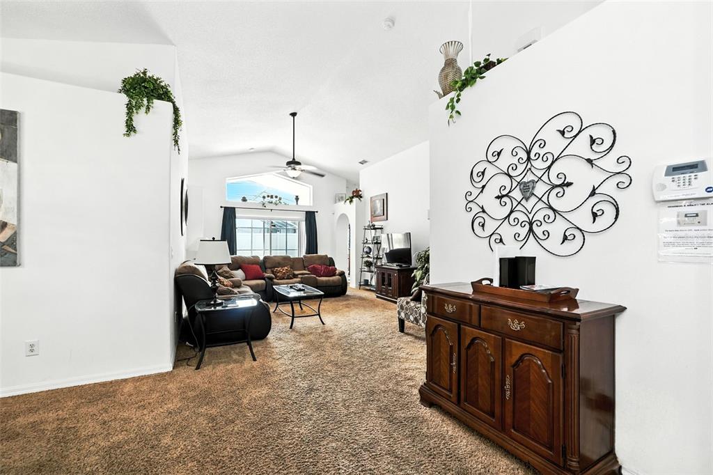 A living room features brown carpeting, a dark wood sideboard, and a sectional sofa — 131 S ROMA WAY, KISSIMMEE, FL